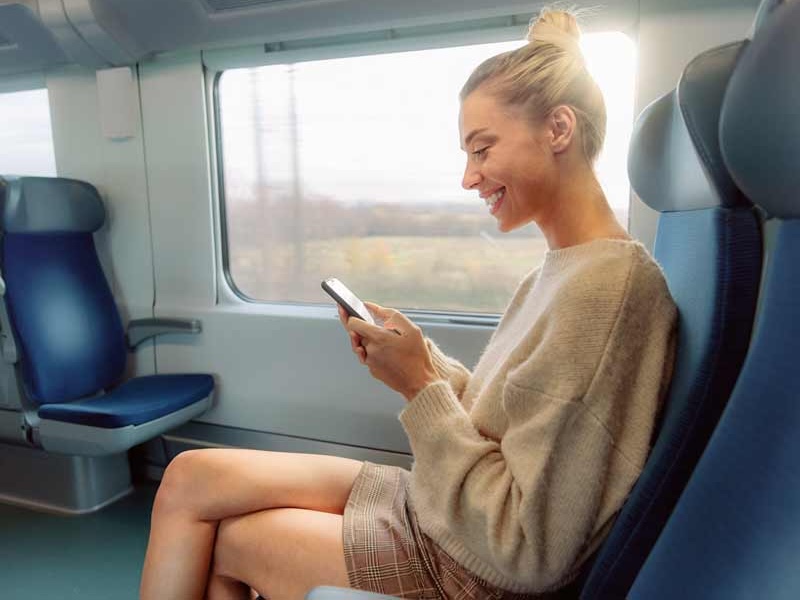 on the go esims for travel lady on a train with a phone